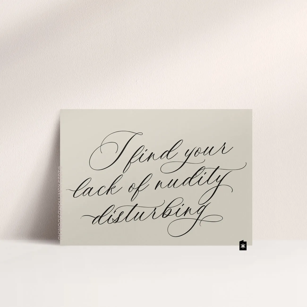 Grey card with black ink printed in script font on the front that says "I find your lack of nudity disturbing" made in Perth WA by Kunty Kards