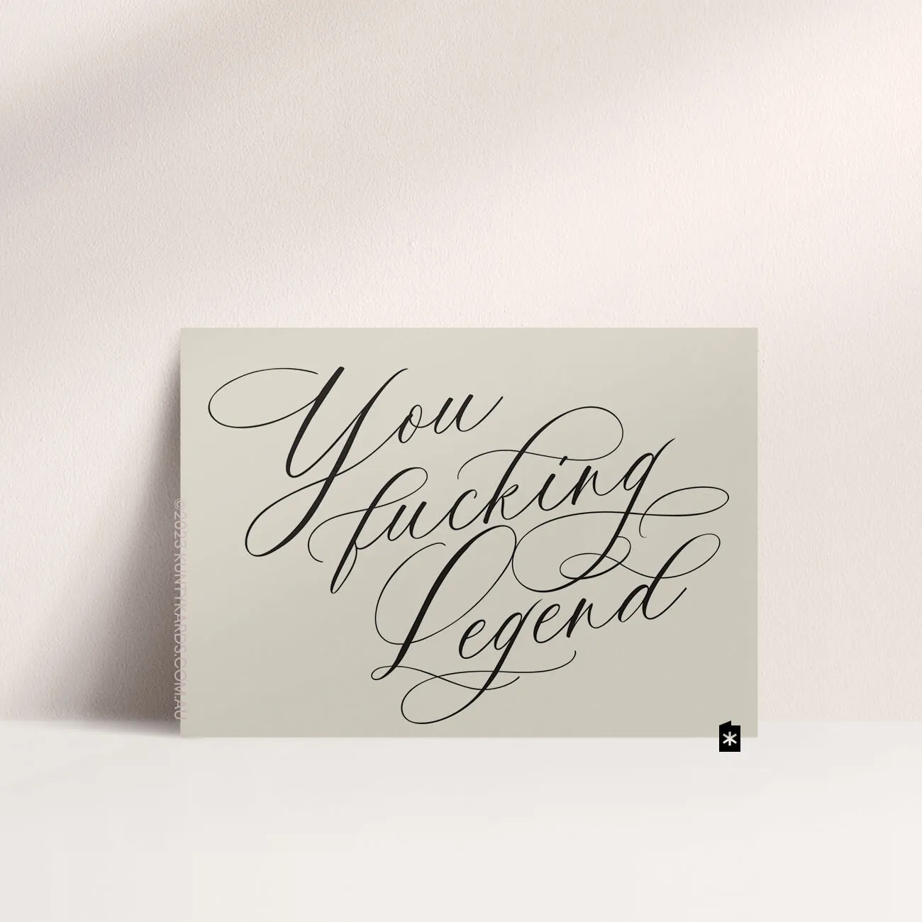 Grey card with black ink printed in script font on the front that says "You fucking legend" made in Perth WA by Kunty Kards