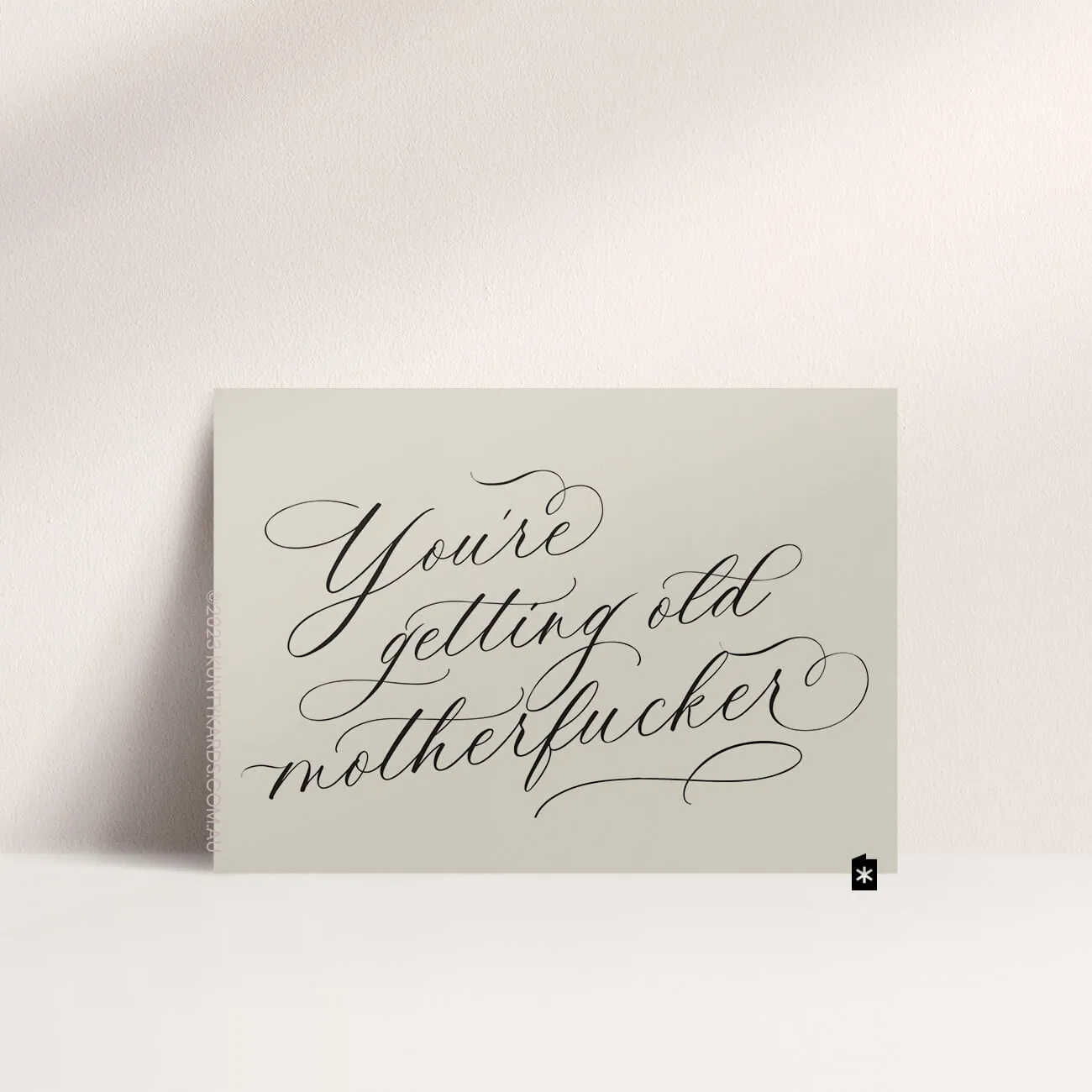 Grey card with black ink printed in script font on the front that says "You're getting old motherfucker" made in Perth WA by Kunty Kards