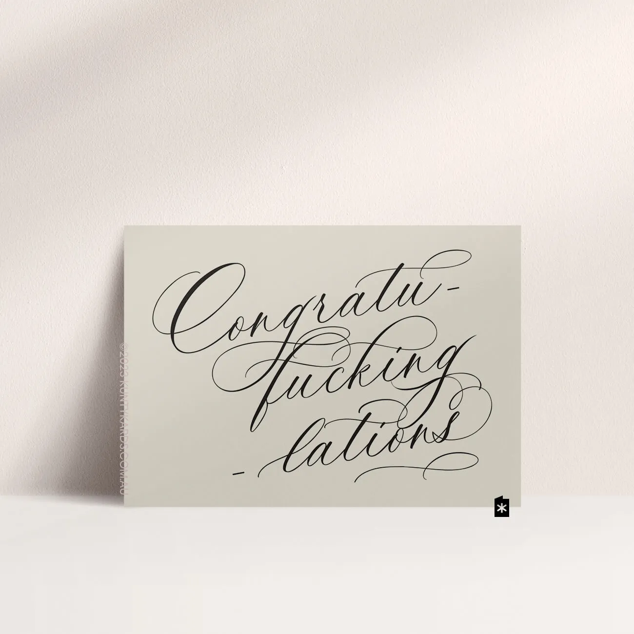 Grey card with black ink printed in script font on the front that says "Congratufuckinglations" made in Perth WA by Kunty Kards