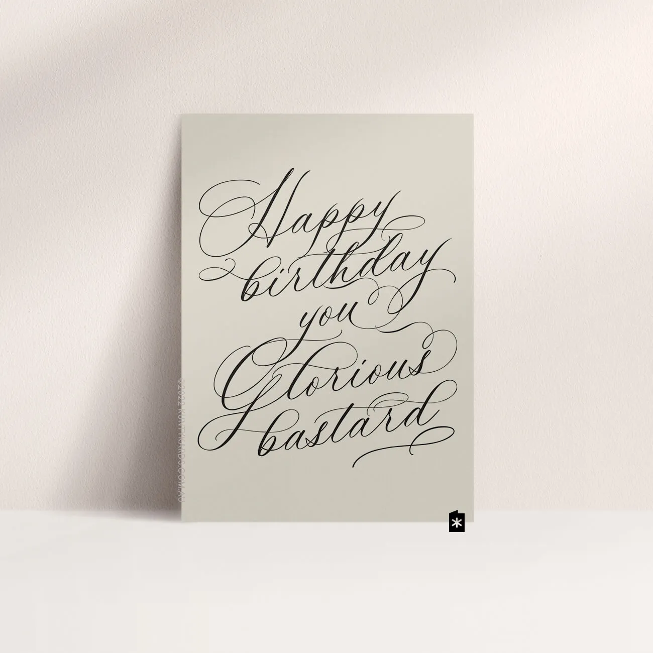 Grey card with black ink printed in script font on the front that says "Happy birthday you glorious bastard" made in Perth WA by Kunty Kards