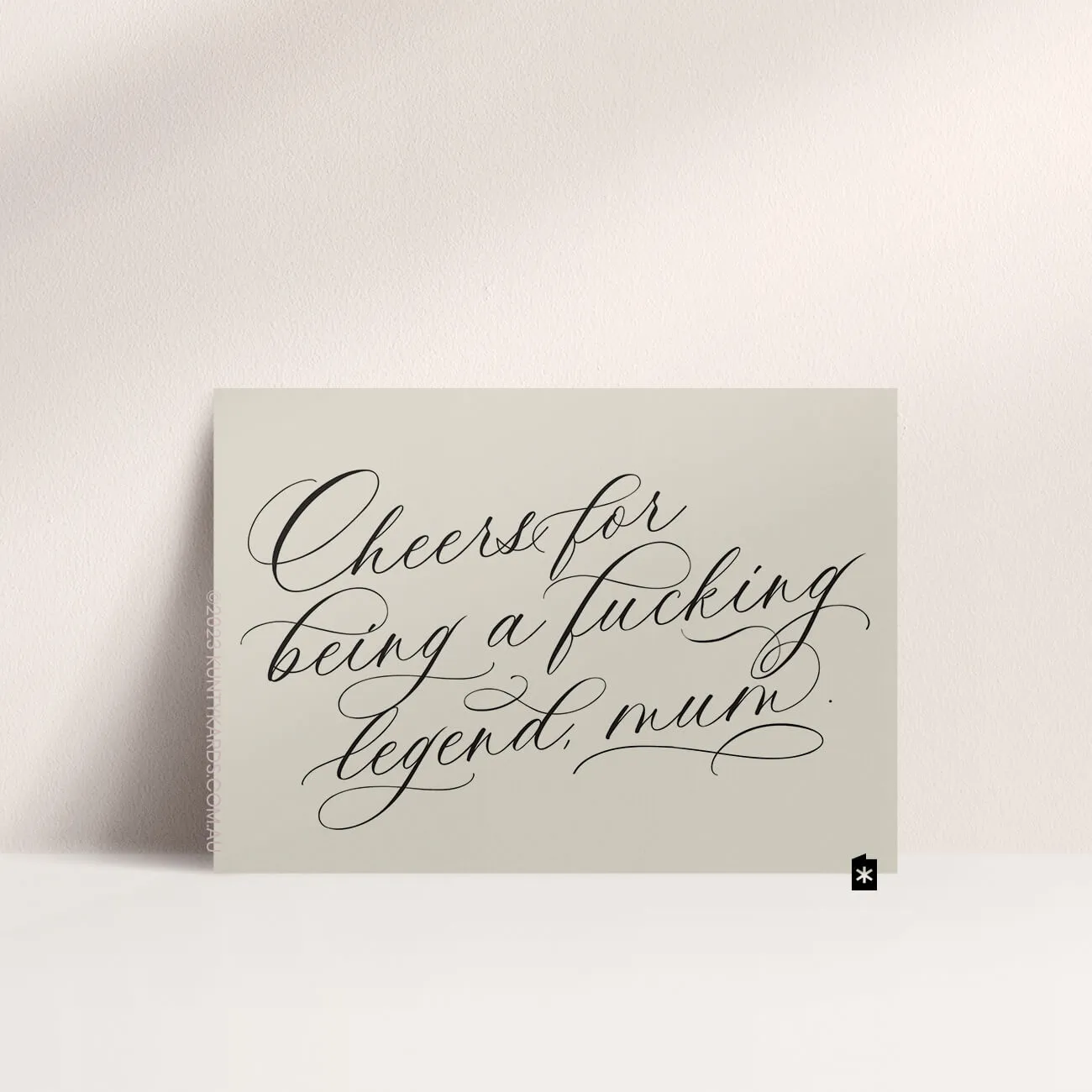 Grey card with black ink printed in script font on the front that says "Cheers for being a fucking legend mum" made in Perth WA by Kunty Kards