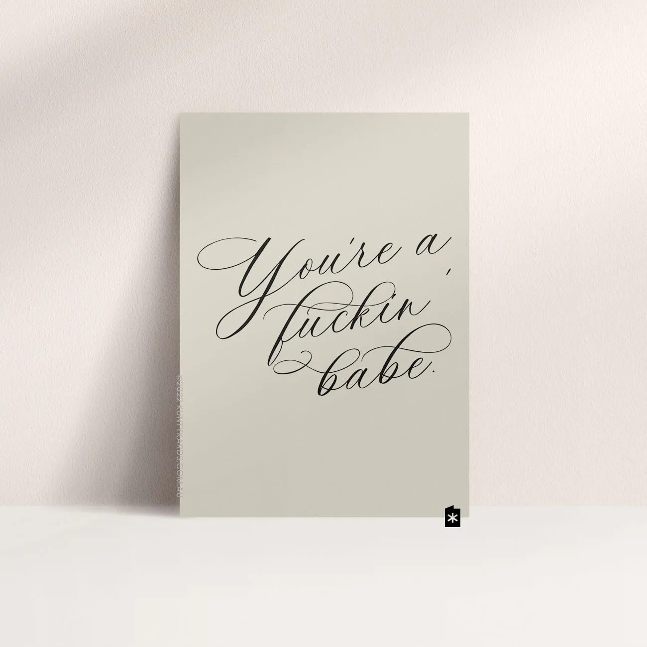 Grey card with black ink printed in script font on the front that says "You're a fucking babe" made in Perth WA by Kunty Kards